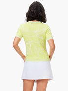Lime green short-sleeved knit top with white, branch-like pattern.  White skirt shown below.