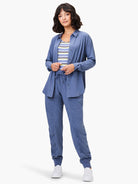 Dusty blue Tech Stretch Shirt, long-sleeved, collared, button-front, shown worn open over a striped top.