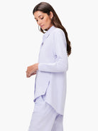 Light lavender collared long-sleeve shirt with a relaxed fit and high side splits on the hem, worn by a woman.