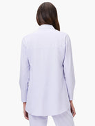Light purple long-sleeved shirt with a collar, back yoke, and rounded hem. Model seen from behind.