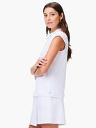 White sleeveless snap-neck top, shown with white skirt; small logo on lower back.