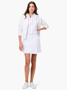 White zip-up jacket, white collared shirt, and white wrap skirt on a model.