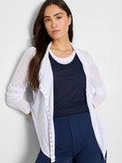 White gauzy cardigan with long sleeves and silver snap closures down the front.  The model is wearing it over a dark navy...