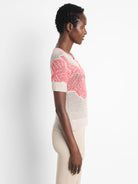Beige short-sleeve mesh sweater with coral-pink  pattern.  Short sleeves, V-neck.