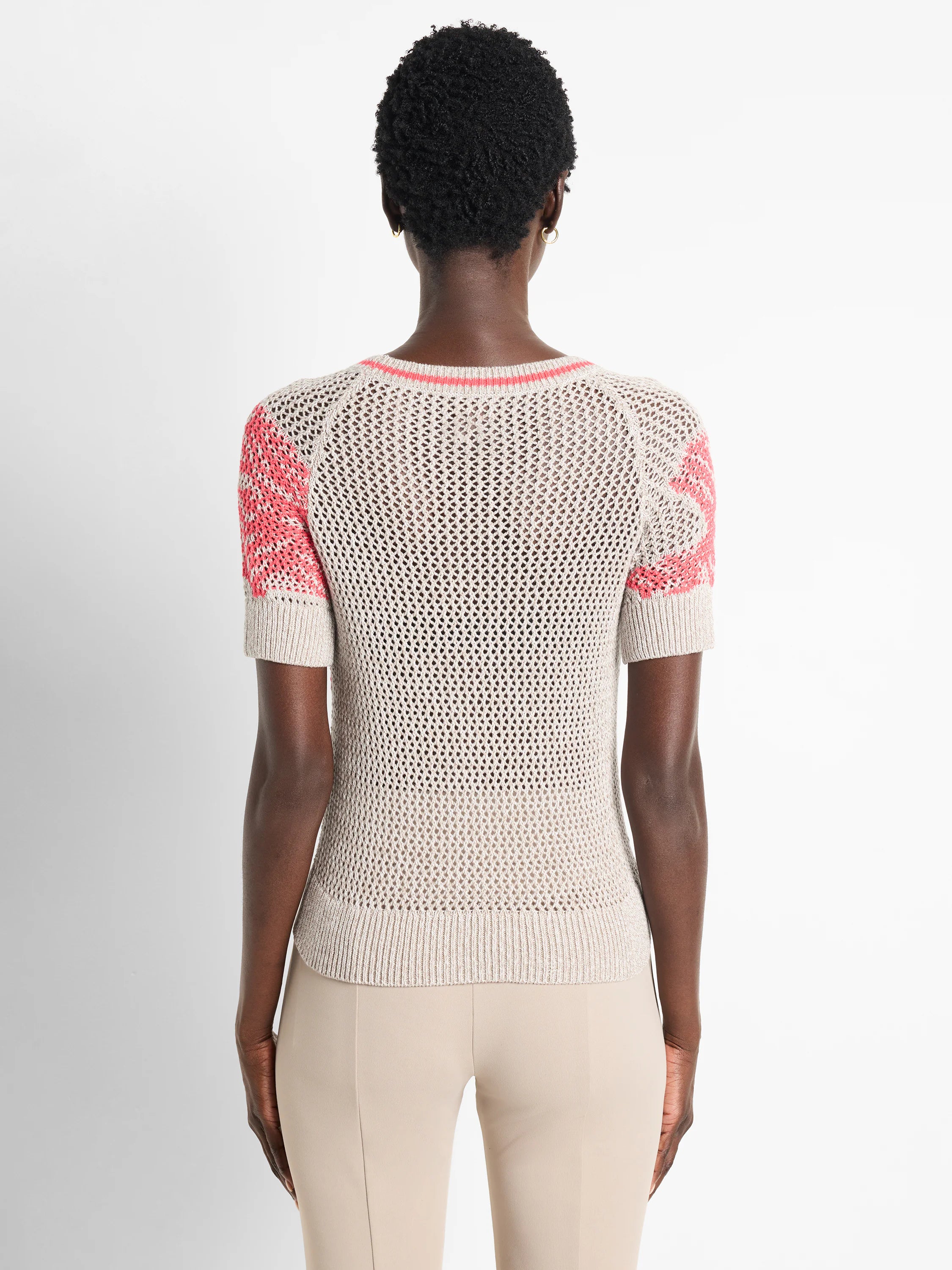 Beige mesh short-sleeved sweater with coral accents at neckline and sleeves.  Back view.