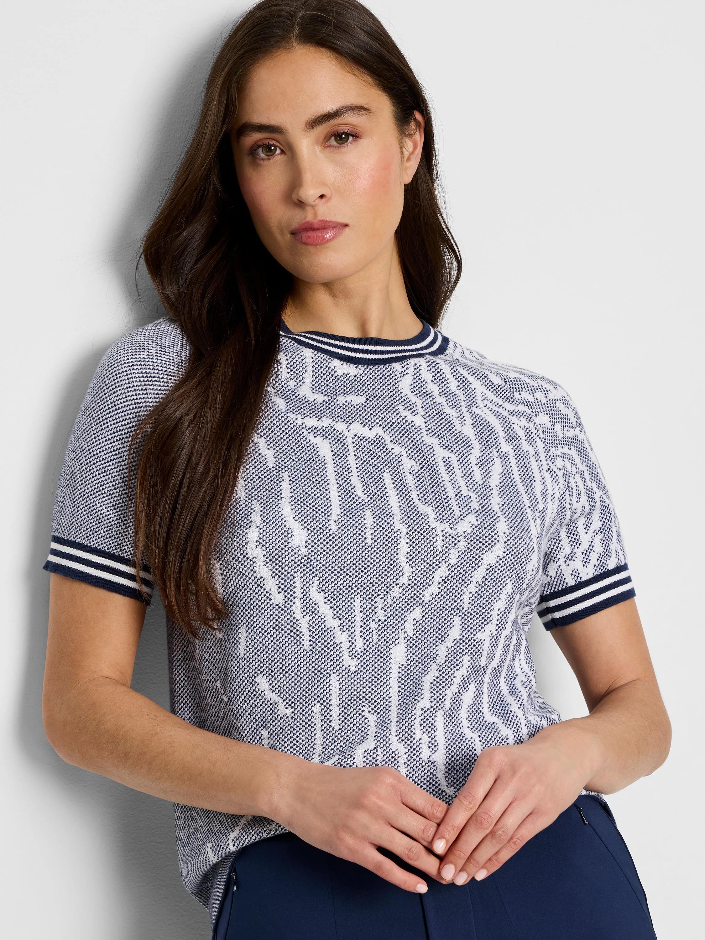 Short-sleeved navy and white sweater tee.  White abstract pattern on navy background.  Navy and white striped cuffs.