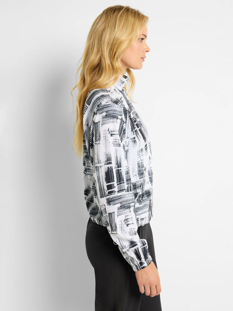 White popover with black abstract brushstroke pattern, long sleeves, and a mock neck.
