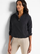 Black, half-zip pullover with long sleeves and drawstring hem.  Model also wearing light beige pants.