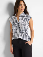 White sleeveless snap-neck top with black brushstroke pattern.