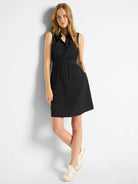 Black sleeveless shirt dress with buttons, pockets, and fitted waist.  Model wears off-white sneakers.