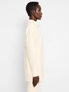Off-white tunic with funnel neck, long sleeves, and a side pocket.