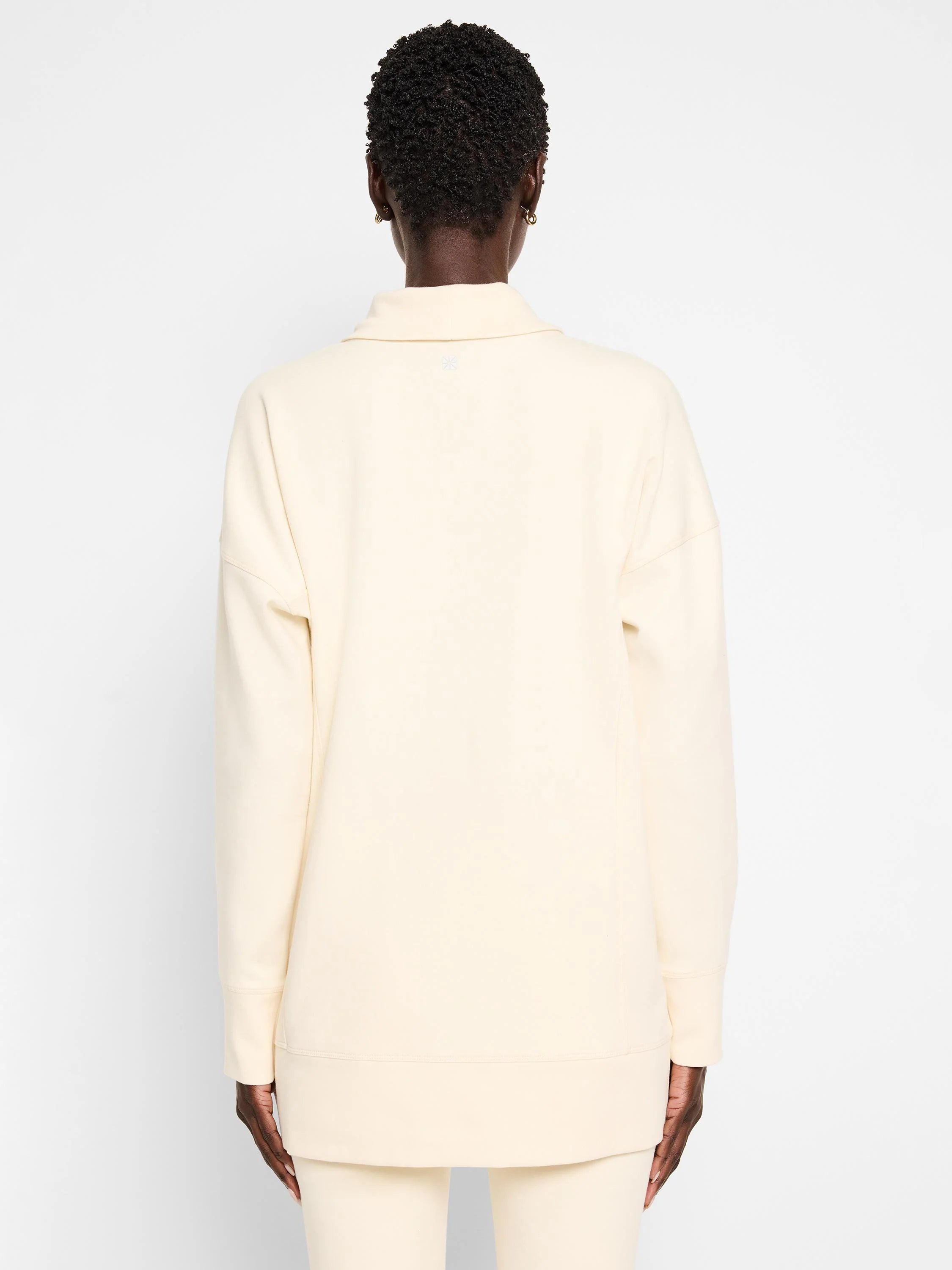 Off-white tunic with funnel neck and long sleeves; seams visible.  Back view.