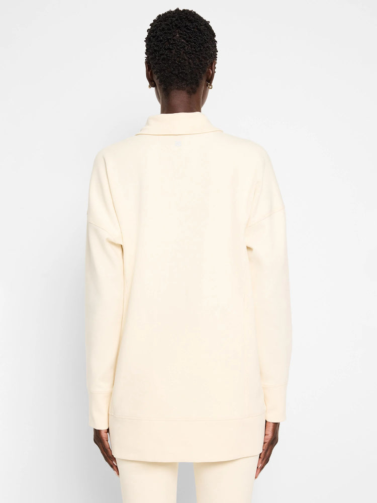 Off-white tunic with funnel neck and long sleeves; seams visible.  Back view.