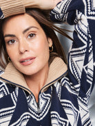 Navy blue sweater with off-white geometric pattern and tan collar; half-zip closure.