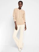 Beige cable-knit hooded sweater with off-white drawstring.