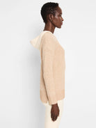 Beige cable-knit hooded sweater.  Off-white hood.  Long sleeves.