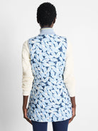 Reversible vest; one side blue with a light blue and white leaf print, the other side is not visible. Quilted.