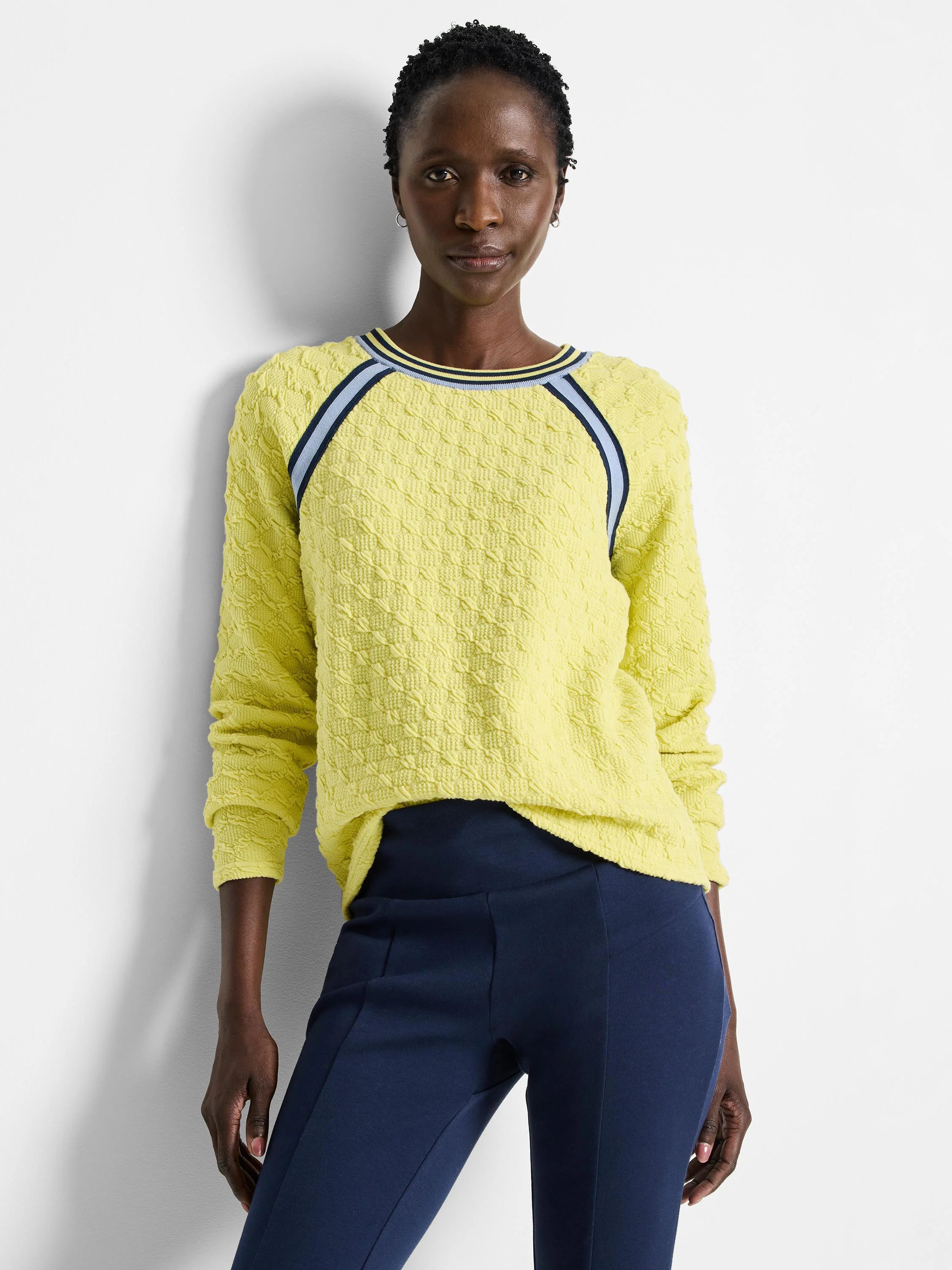 Pale yellow textured pullover sweater with navy and light blue stripes at neckline and shoulders. Long sleeves.
