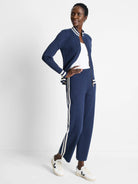 Navy blue ribbed track jacket with cream stripes on cuffs and zipper placket. Matching pants have cream side stripes.