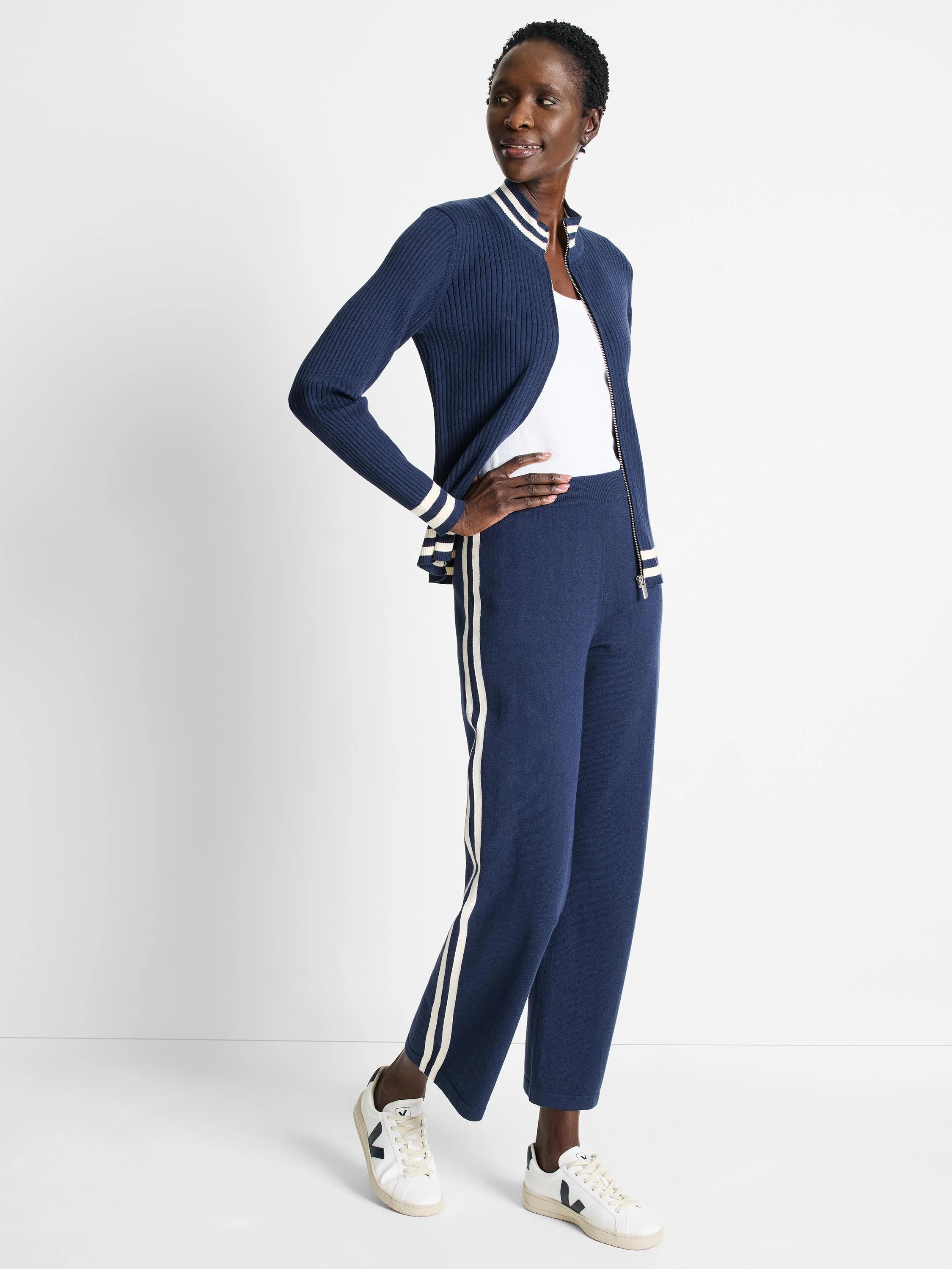 Navy blue ribbed track jacket with cream stripes on cuffs and zipper placket. Matching pants have cream side stripes.