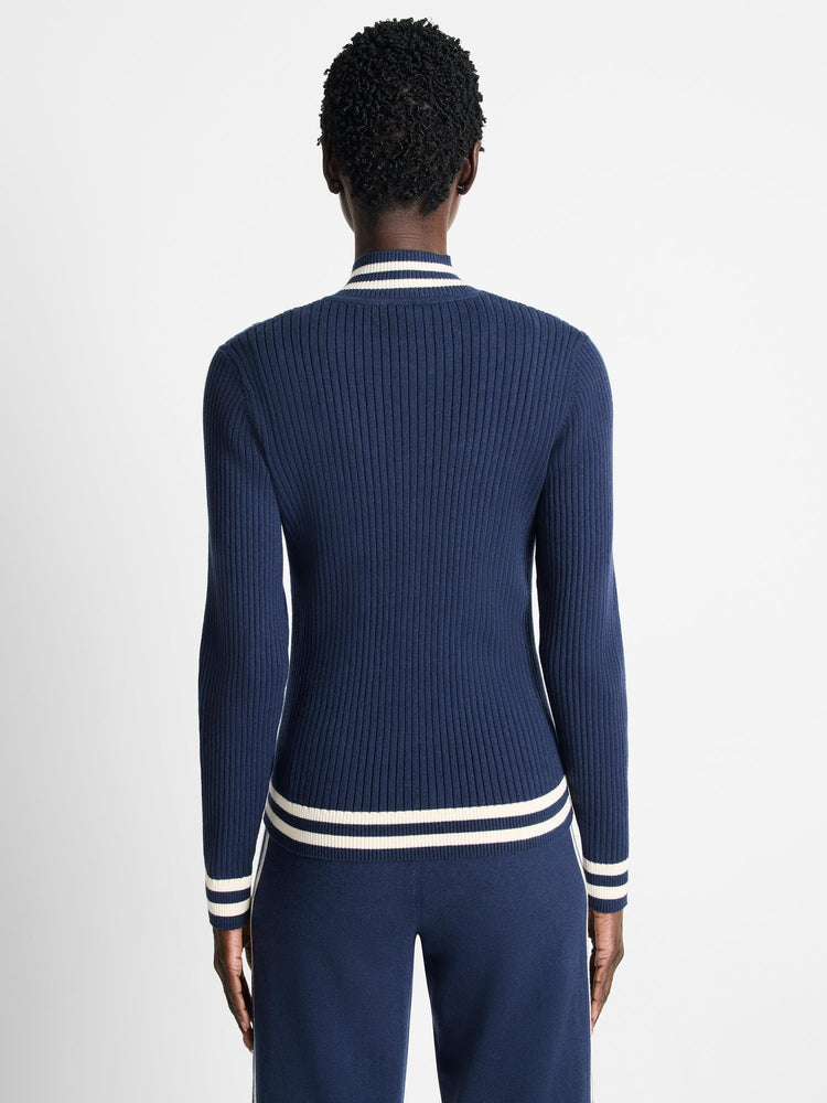 Navy blue ribbed knit track jacket with off-white/cream stripes at cuffs and hem.  Shown from the back.