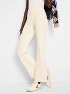 Off-white bootcut pants with a high waist.  Seams are visible.  Model also wears white and tan sneakers.