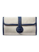 Natural linen clutch with navy blue leather trim, central strap & oval loop closure. White stitching.