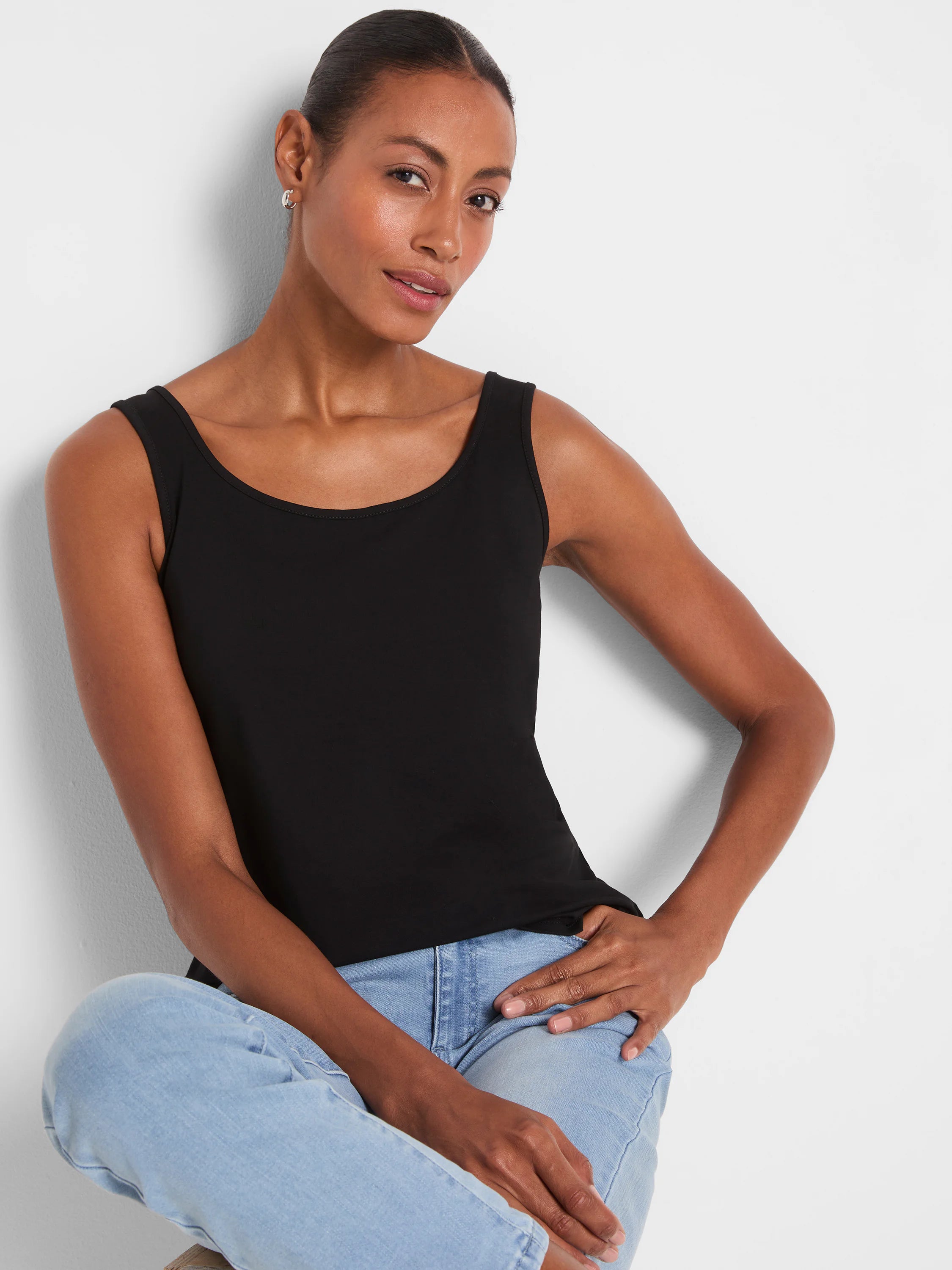 Black tank top featuring a wide scoop neckline and broad shoulder straps. Smooth, slightly fitted fabric.