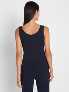 Navy sleeveless tank top with a scooped back and a curved shirt tail hem, worn by a model from the back.