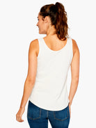 Off-white sleeveless tank with a scoop back and curved shirt-tail hem, worn by a woman.