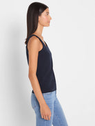 Navy tank top with wide straps and a scoop neck worn by a woman shown in profile.