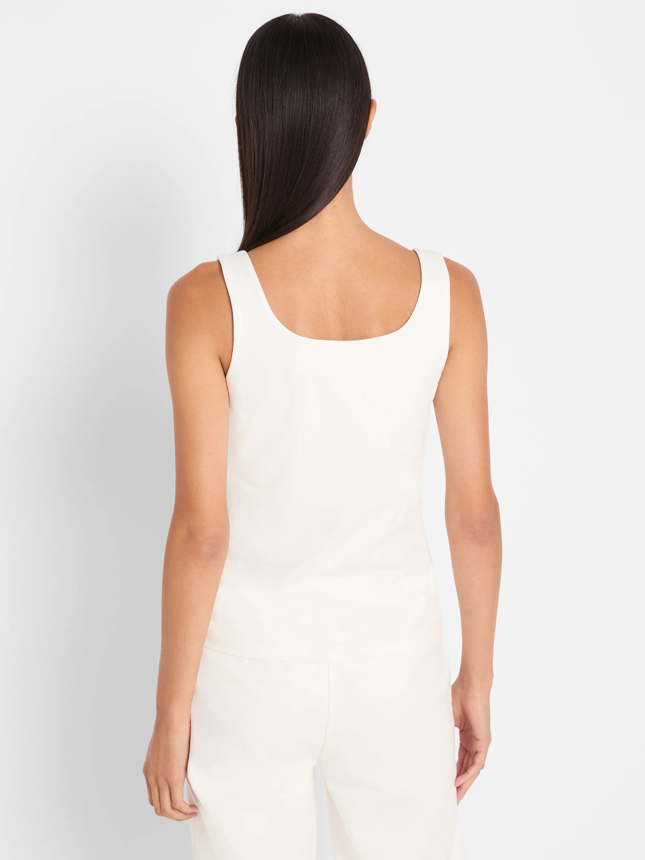 Back view of an off-white tank top with a square neckline and wide straps on a person.
