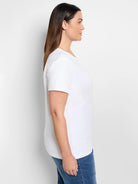 White, short-sleeve crew neck t-shirt on a woman, shown in side profile, paired with blue jeans.