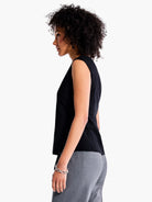 Black sleeveless V-neck top shown from the side.  Model wears gray pants.