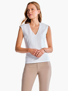 White sleeveless V-neck top;  model wears taupe pants.