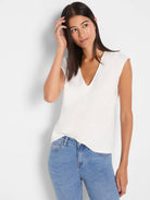 Off-white V-neck top featuring cap sleeves and a smooth, flowing fabric texture.