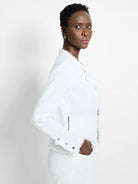 Off-white textured knit jacket with fringe along collar, front & cuffs. Features silver zippers & stud details.