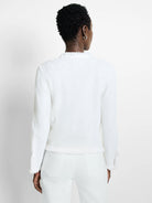 White textured knit jacket with fringe trim at the neckline, hem, and sleeve cuffs.