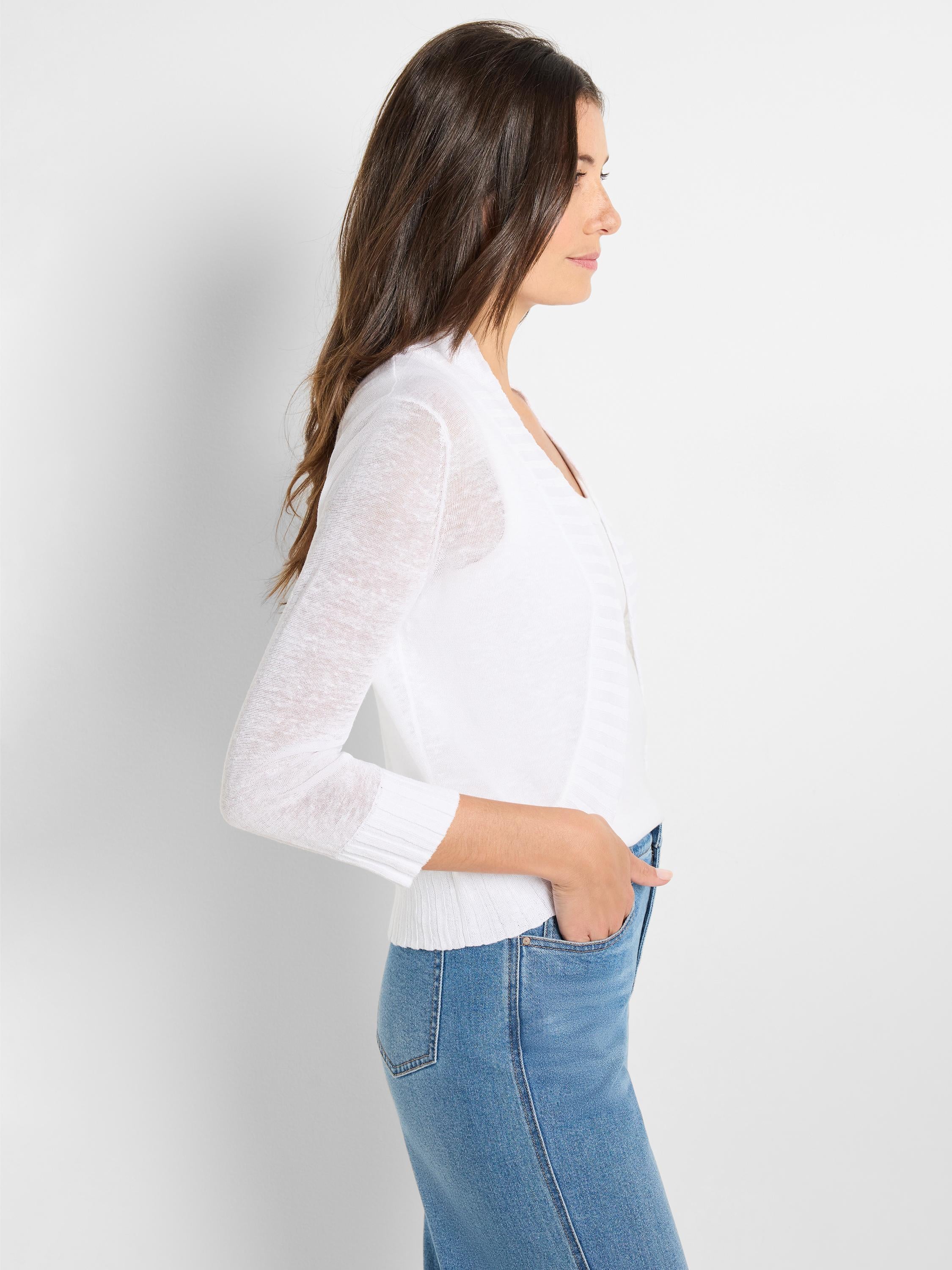 Fitted white semi-sheer knit open cardigan with long sleeves and ribbed cuffs is styled casually.