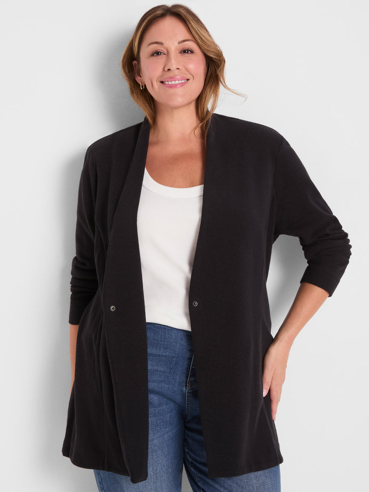 Model wears a relaxed fit black longline knit cardigan with a draped collar and hidden snap closure.