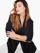 The model wears a black, relaxed fit, open-front knit jacket with a wide shawl collar.