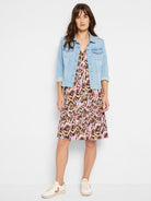 Cropped light wash denim jacket with a frayed hem is paired over a v-neck multicolored tiered print mini-dress.