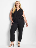 Black sleeveless V-neck top, relaxed fit. Model wears it with tailored black pants.