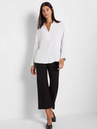 White flowing blouse with a notch V-neck, long cuffed sleeves, and a relaxed fit.