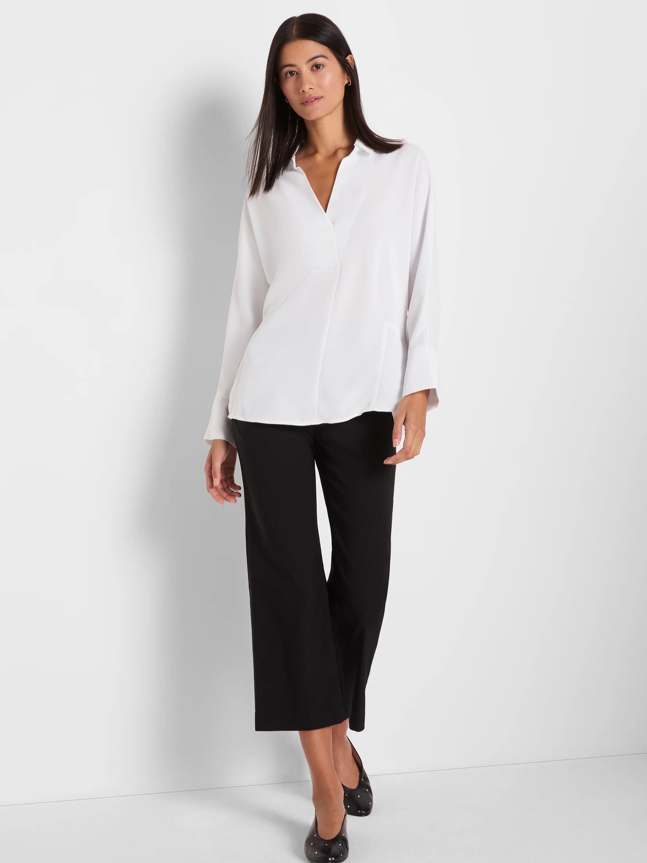 White flowing blouse with a notch V-neck, long cuffed sleeves, and a relaxed fit.