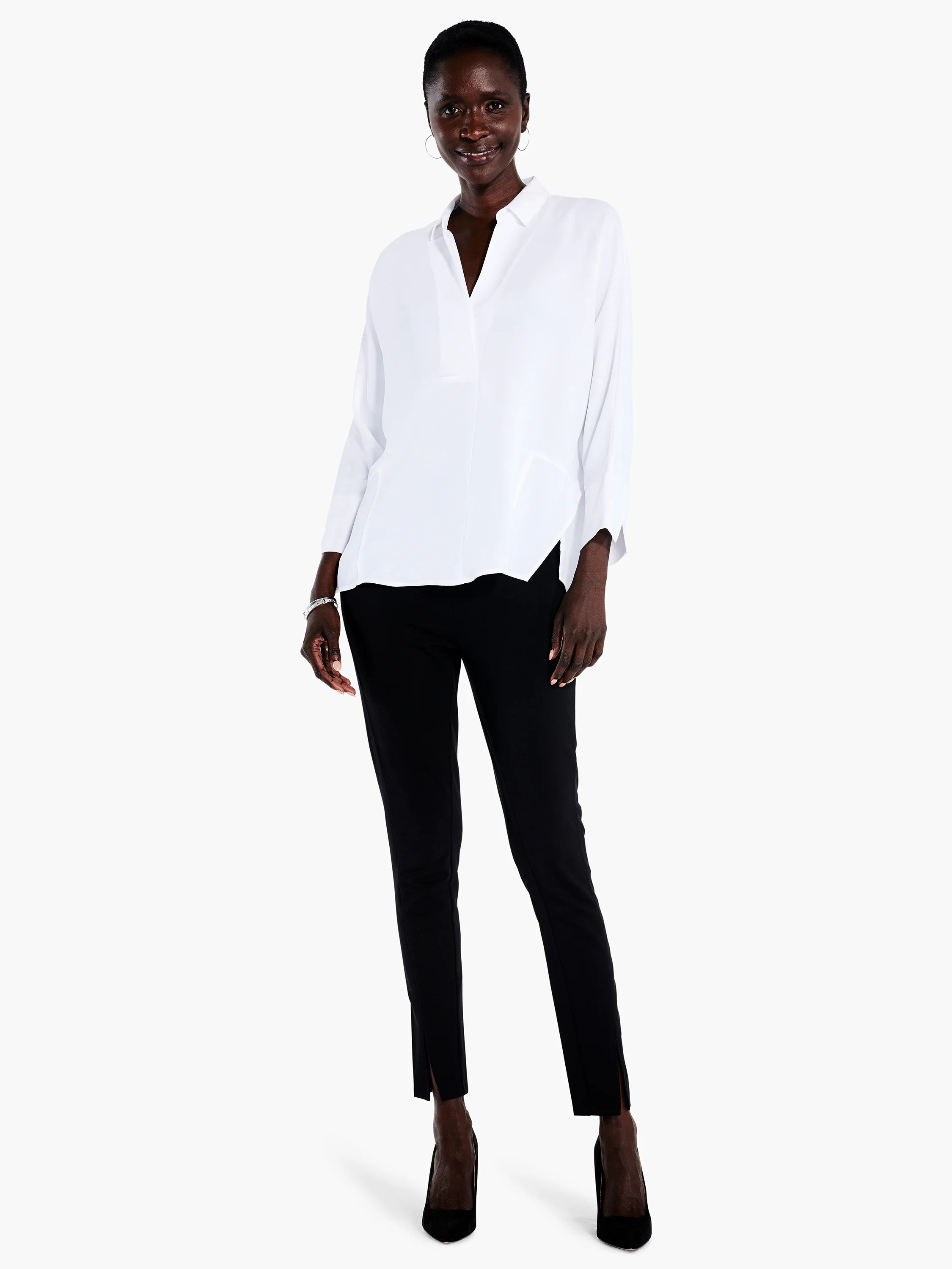 White collared blouse, 3/4 sleeves, asymmetrical hem. Model wears black pants & shoes.