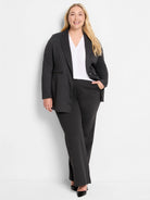 White cap sleeve V-neck top, worn layered under a dark gray pinstripe blazer.