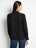 Black popover shirt. Long sleeves with light button cuffs, collared, relaxed fit, and a back yoke detail.