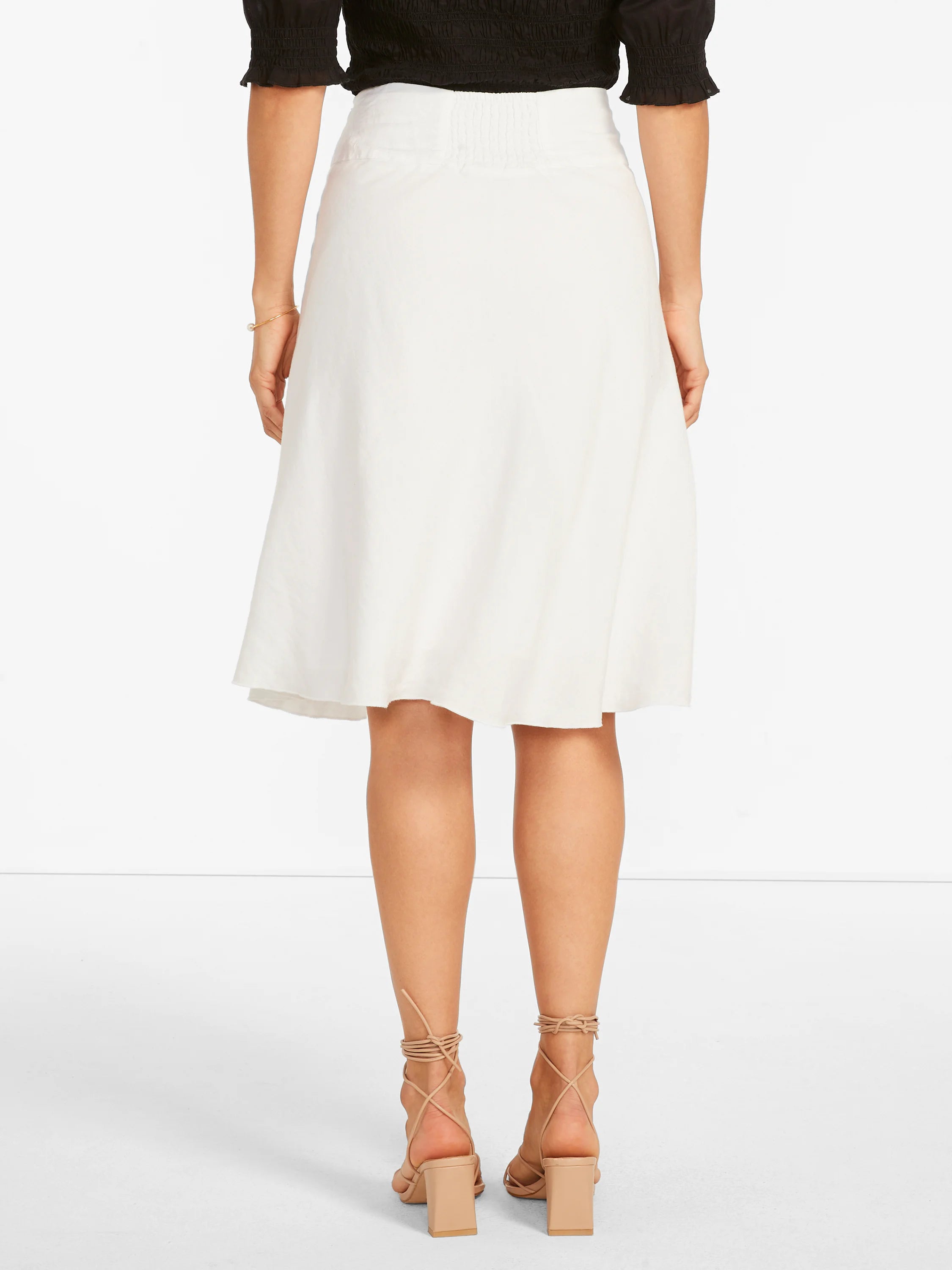 White, knee-length A-line skirt with a shirred elastic waistband at the back.