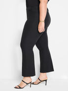Black demi-boot pants, fitted through the thigh, with a subtle flare at the ankle. Smooth, slightly structured fabric.